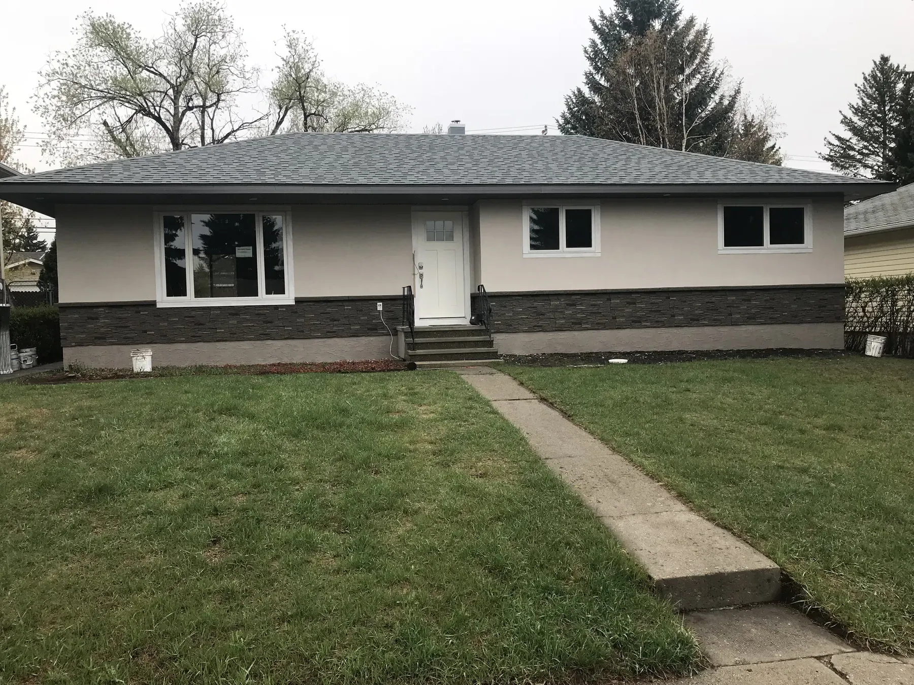 Calgary bungalow after an exterior renovation with stucco and stone skirting